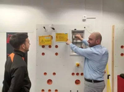 Trainer und Lehrling vor Elektowand
