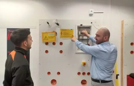 Trainer und Lehrling vor Elektrowand