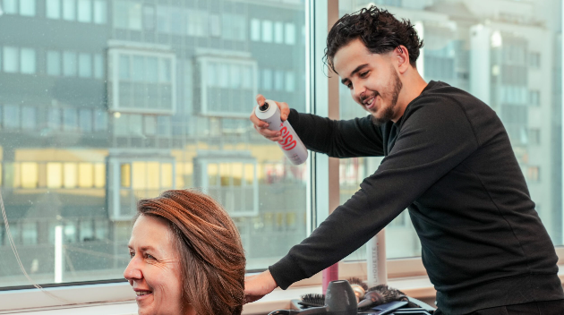 Lehrling mit Haarspraydose styled Haare