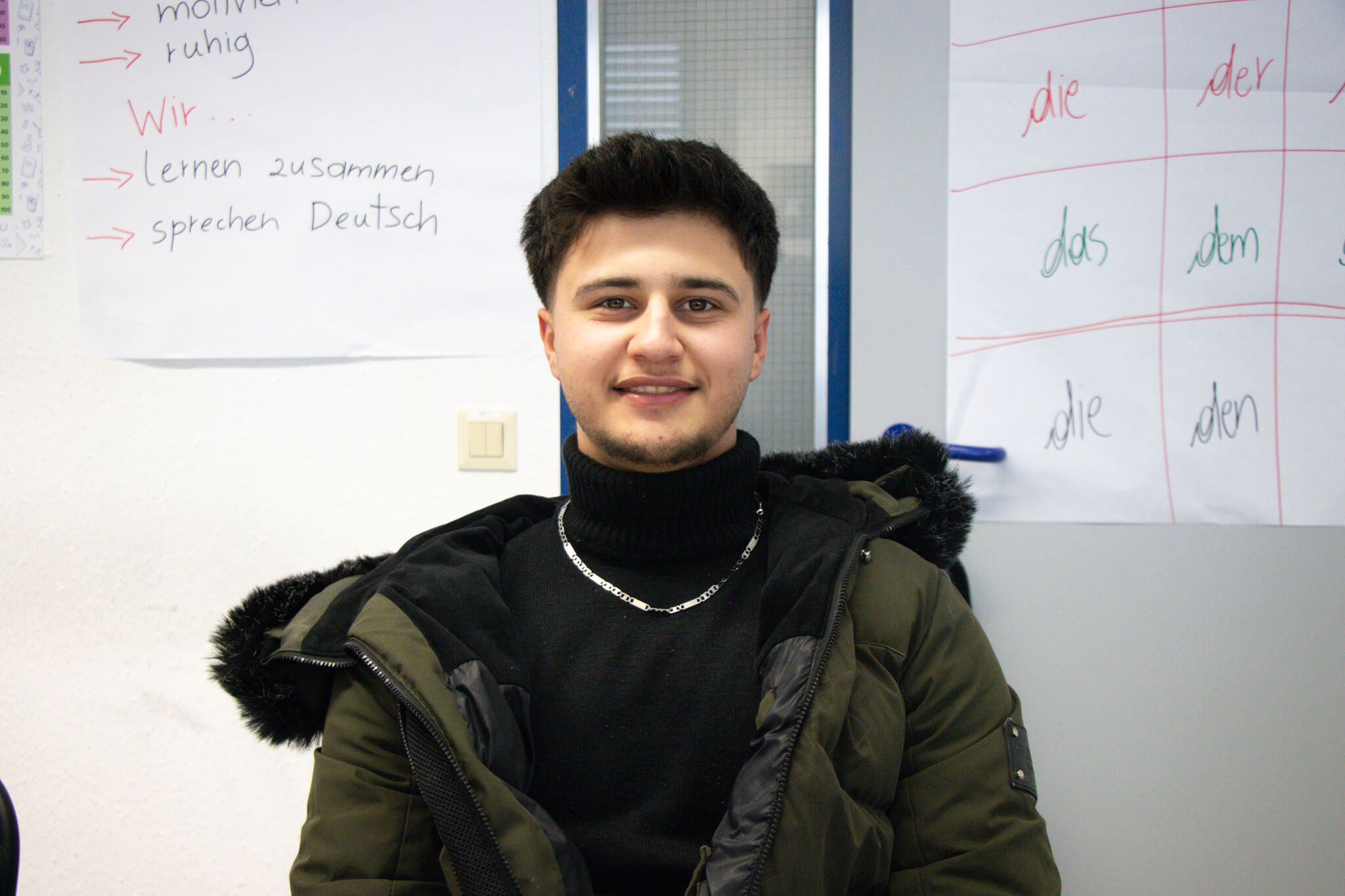 Zu sehen ist der junge Schüler und Kursteilnehmer Aziz Osman, der in die Kamera strahlt.