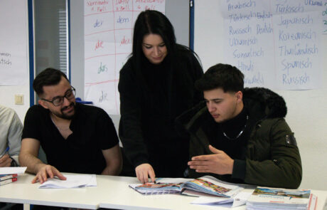 buesra-yavuz-ipcenter Zu sehen ist Trainerin Büsra Yavuz, wie sie 2 Schülern etwas erklärt und vorliest.