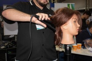 Lehrling der ÜBA Friseur:in beim Tag der Lehre XXL beim Haare stylen