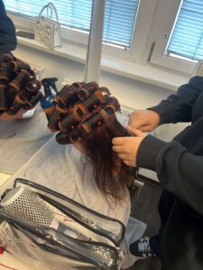 Lehrling der ÜBA FriseurIn beim Locken machen
