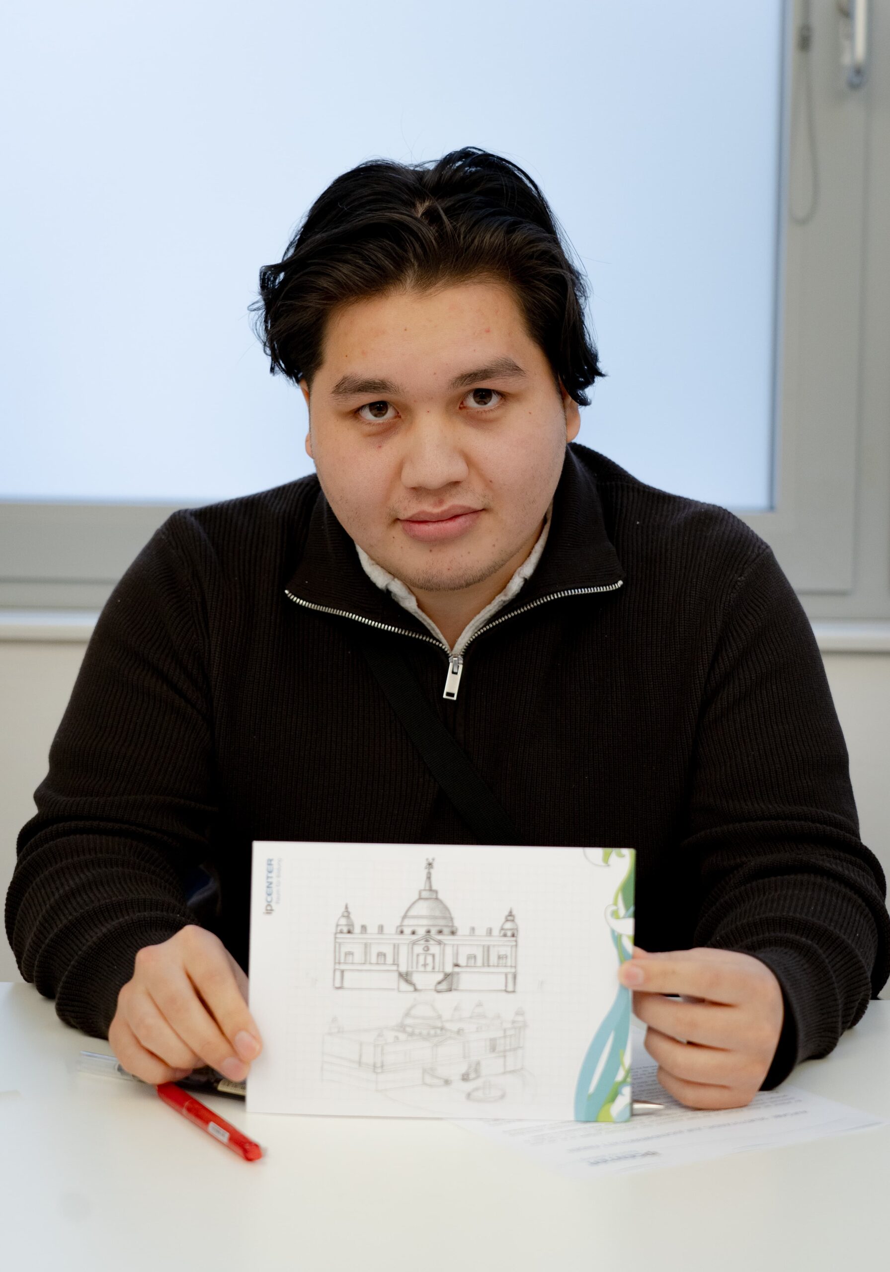 Praktikant Abolfazl Omid mit seiner Zeichnung von einem Schloss